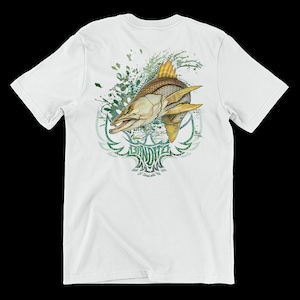 Pode incluir: Camiseta branca com um gráfico verde e amarelo de um peixe saltando para fora da água. O peixe está rodeado de respingos verdes e brancos. O texto "Bandit" está impresso abaixo do peixe.