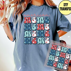 May include: A blue t-shirt with the words "american mama" in a retro font. The word "mama" is repeated four times in a grid pattern, with red, white, and blue star accents. A DTF transfer is visible.