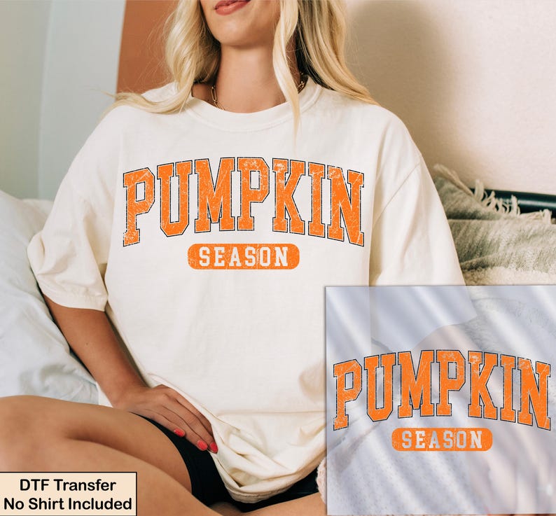 K&ouml;nnte beinhalten: Ein cremefarbenes Kurzarm-T-Shirt mit dem orangefarbenen, abgenutzten Schriftzug PUMPKIN SEASON in College-Schriftart. Das Design zeigt das Wort PUMPKIN in einem gro&szlig;en Bogen &uuml;ber dem Wort SEASON in einem orangefarbenen rechteckigen Rahmen.