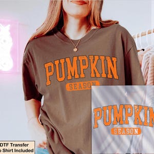 K&ouml;nnte beinhalten: Ein dunkelbraunes Kurzarm-T-Shirt mit dem Text PUMPKIN SEASON in einer abgenutzten orangefarbenen College-Schriftart auf der Brust. Das Shirt hat einen Rundhalsausschnitt und eine lockere Passform. Der Text DTF Transfer No Shirt Included ist unten links zu sehen.