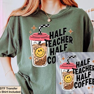 May include: A dark olive green t-shirt featuring a graphic of an iced coffee cup with a pink lid, a checkered straw, and a yellow smiley face. The text reads HALF TEACHER HALF COFFEE, accompanied by small four-pointed star icons in a light orange color.