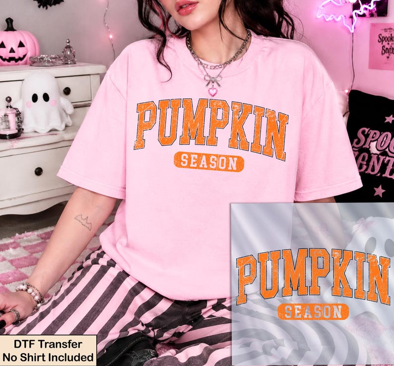 K&ouml;nnte beinhalten: Ein hellrosa Kurzarm-T-Shirt mit dem Text PUMPKIN SEASON in einer abgenutzten orangefarbenen College-Schriftart. Das Design ist mittig auf der Brust platziert. Eine separate Grafik&uuml;berlagerung zeigt dasselbe orangefarbene Textdesign.