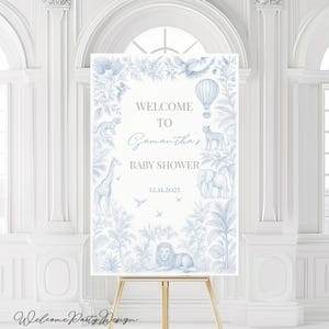 Puede incluir: Un letrero de bienvenida para baby shower en azul claro y blanco, con ilustraciones de animales de la jungla, como una jirafa, un león y un elefante. El letrero dice "Welcome to Samantha's Baby Shower 12.11.2025". Se muestra en un caballete de madera.