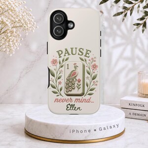 May include: A cream-colored phone case featuring a central mahjong tile with a peacock illustration and the number 1. The design includes green leafy branches, pink flowers, and the text PAUSE never mind... Ellen in green and pink script.