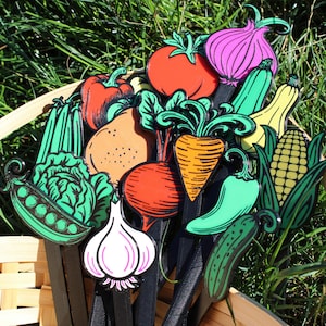 May include: A collection of colorful, wooden vegetable cutouts, including a tomato, onion, carrot, and corn, arranged in a woven basket. The vegetables are painted with bright colors and outlined in black, creating a whimsical garden theme.