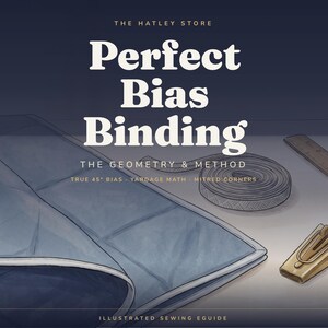 Könnte beinhalten: Ein illustrierter Näh-Ratgeber mit dem Titel The Hatley Store Perfect Bias Binding The Geometry & Method. Das Bild zeigt ein blaues Stoffstück mit Einfassung, eine Rolle Schrägband, einen metallenen Schrägbandformer und ein Holzlineal.