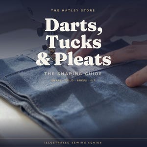 Puede incluir: Una pieza de tela azul siendo cosida bajo una aguja de máquina con el texto superpuesto: THE HATLEY STORE, Darts, Tucks & Pleats, THE SHAPING GUIDE, SHAPE · FOLD · PRESS · FIT, e ILLUSTRATED SEWING EGUIDE en fuentes blancas serif y sans-serif.