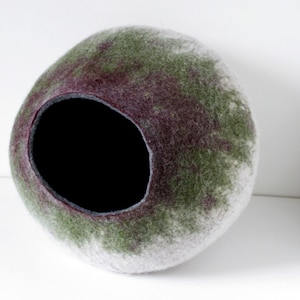 May include: A round, felted pet bed with a large opening. The bed is a mix of white, green, and purple.