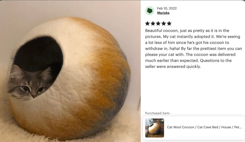May include: A white, yellow, and gray cat bed shaped like a sphere with a cat inside. The bed is made of wool felt and has a round opening for the cat to enter.