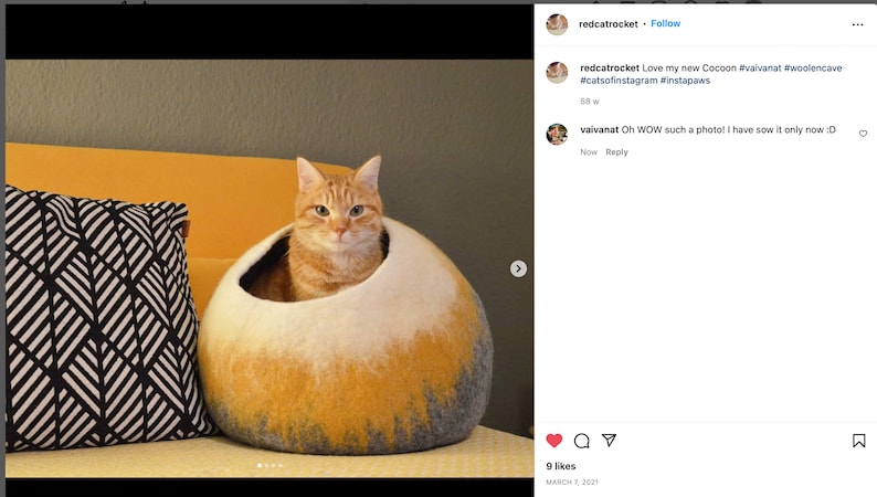 May include: A ginger cat sits inside a round, yellow and white felt cat bed. The bed is on a couch with a black and white patterned pillow.