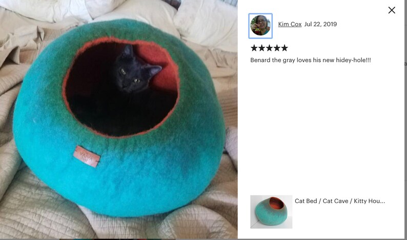 May include: A teal and orange cat bed made of felted wool. A gray cat is inside the bed. The bed is on a white and beige blanket. The text "Cat Bed / Cat Cave / Kitty Hou..." is visible in the image.