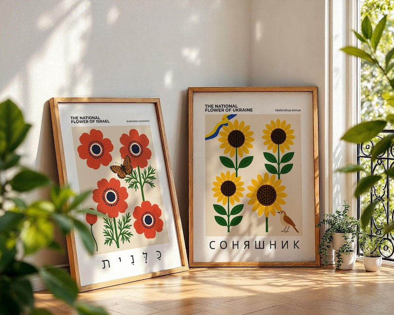 May include: Two framed art prints featuring floral designs. One print displays red flowers with a butterfly, the text "THE NATIONAL FLOWER OF ISRAEL", and Hebrew text. The other print shows sunflowers, the text "THE NATIONAL FLOWER OF UKRAINE", and the Ukrainian word "СОНЯШНИК".