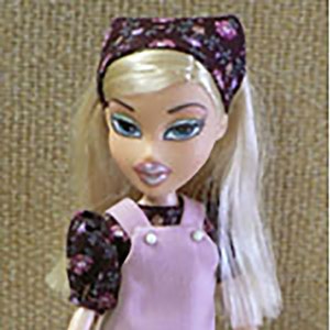 May include: A doll wearing a pink jumper with a floral print blouse and a headband. The doll is wearing sneakers. The image also shows a pattern for a jumper and blouse set with a heart print. The pattern includes a headband. The text #95141 jumper & blouse set is visible in the image.