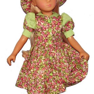 Pode incluir: Uma boneca vestindo um vestido floral verde e rosa com um chapéu combinando. A boneca tem cabelo loiro e olhos azuis.