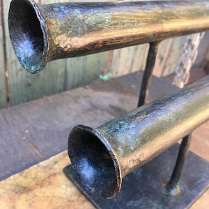 May include: A double-tiered jewelry stand with two black and gold metal tubes. The tubes have a distressed finish with a teal and copper patina.