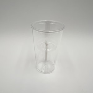 May include: A clear, transparent plastic cup featuring a double-walled design with a visible internal structure. The cup has a smooth, cylindrical shape with a slightly tapered base and a wide, open rim at the top, showcasing a clean and simple aesthetic.