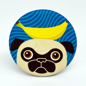 May include: A blue and white striped button with a cartoon pug wearing a yellow banana on its head.