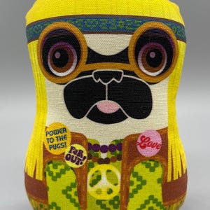 May include: A yellow plush toy pug wearing a headband, round glasses, and a green and brown vest with peace sign and other patches that say "Power to the Pugs!" and "Far Out!"
