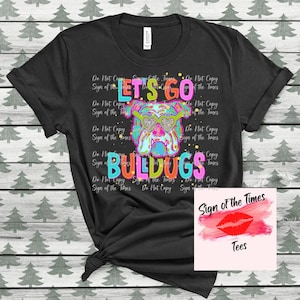 May include: Black t-shirt with a colorful graphic of a bulldog wearing sunglasses and the text "Let's Go Bulldogs". The text "Sign of the Times" is also on the shirt.