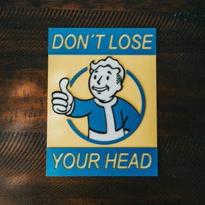 May include: A rectangular sign with the text "DON'T LOSE YOUR HEAD" in blue letters. The sign features a cartoon character giving a thumbs-up inside a blue circle, set against a yellow background.