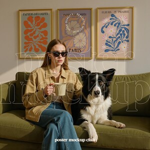 Pu&ograve; includere: Una donna con occhiali da sole e una giacca marrone &egrave; seduta su un divano verde con un border collie bianco e nero. Tre poster incorniciati con motivi floreali sono appesi al muro dietro di loro. I poster sono intitolati "Papiers Decoup&eacute;s", "Papiers Derigit&eacute;s" e "Fleurs de Prairie".