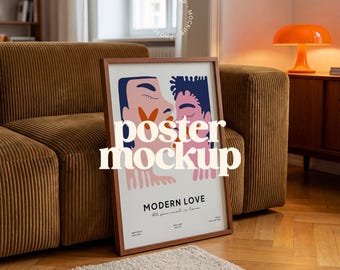 May include: A framed poster with the words "poster mockup" in a stylized font. The poster features an illustration of two figures embracing, with the words "MODERN LOVE" and "All you need is love" below. The poster is leaning against a brown corduroy sofa.