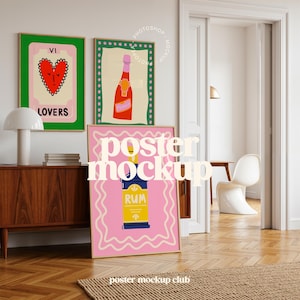 May include: Three framed art prints with vibrant illustrations. One shows a heart with the word "LOVERS", another a champagne bottle, and the third a rum bottle with the word "RUM". The prints are displayed in a room with a wooden cabinet and a white lamp.