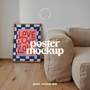 Könnte beinhalten: Ein gerahmtes Poster mit einem blau-weiß karierten Hintergrund und einem rosa Rechteck mit dem Wort "LOVE", das in roten Buchstaben wiederholt wird. Das Poster lehnt an einem beigen Cord-Sofa.