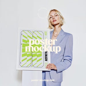 May include: A woman wearing a light blue blazer holds a framed poster mockup featuring a green and white geometric pattern. The poster includes the text "poster mockup" and "aesthetic". The poster is labelled "#005".