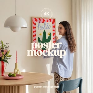 Könnte beinhalten: Ein gerahmtes Poster mit einer Kaktusillustration und dem Wort "hello" in einer verspielten Schriftart. Das Poster befindet sich in einem Holzrahmen und wird von einer Person gehalten. Das Bild zeigt auch einen runden Holztisch, eine Vase mit Blumen und eine Hängeleuchte.