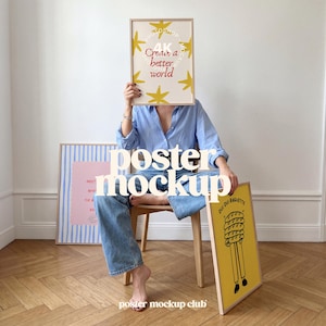 May include: A light blue button-down shirt and blue jeans with three framed posters. One poster features yellow stars and the text "Create a better world". Another has blue stripes and pink text. The third is yellow with a baguette illustration.