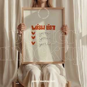 May include: A wooden framed poster mockup with a white background and the text "WISH LIST" in orange and brown lettering. The text "you" is repeated four times in black lettering below the title. The poster is being held by a person wearing white pants.