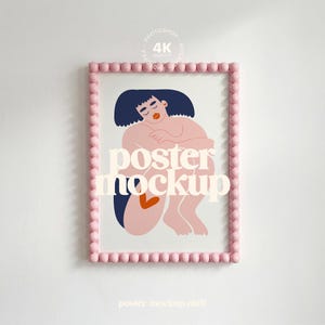 Könnte beinhalten: Gerahmter Poster-Mockup mit einer minimalistischen Illustration einer sitzenden Person mit dunkelblauen Haaren und einem herzförmigen Detail. Der rosa Rahmen hat ein Perlendesign, und der Text "poster mockup" ist auf dem Bild überlagert.