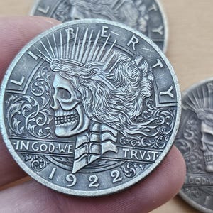 May include: Silver-toned coin with a detailed design of a skull with a crown and the words "LIBERTY", "IN GOD WE TRVST", and "1922".