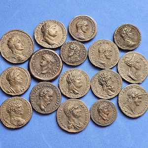 Puede incluir: Una colección de antiguas monedas romanas de bronce, cada una con un perfil de una figura histórica e inscripciones. Las monedas varían en tamaño y detalle, con desgaste y pátina visibles, sobre un fondo azul.