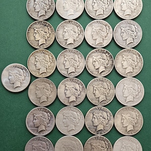 Könnte beinhalten: Eine Sammlung von 25 Peace Dollar Silbermünzen aus den Jahren 1922 bis 1935. Die Münzen zeigen ein Profil von Liberty mit einem strahlenden Sonnenstrahl-Design.
