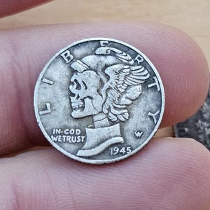 May include: A silver Mercury dime coin from 1945, featuring a profile of a woman with winged hair and the inscription "LIBERTY." The coin also includes the words "IN GOD WE TRUST."