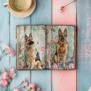 May include: An open book with a floral design on the cover. Two German Shepherd dogs are pictured on the pages. The book is on a light blue and pink wooden surface.
