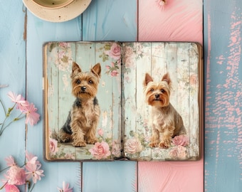 May include: An open vintage-style journal with a floral design on the cover. Two Yorkshire Terrier dogs are pictured on the pages, one on each side. The dogs are brown and tan with black noses and eyes.