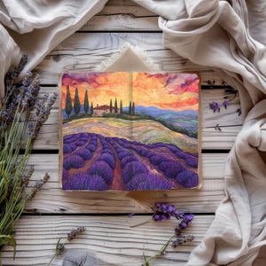 Puede incluir: Un libro abierto con una pintura de acuarela de un campo de lavanda en un paisaje toscano. La pintura representa una puesta de sol con una pequeña casa y árboles en la distancia. El libro está sobre una superficie de madera blanca con flores de lavanda esparcidas alrededor.