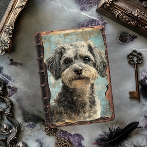 May include: A vintage-style book with a dog portrait on the cover. The dog has gray and tan fur, with a detailed, expressive face. The book's cover has a distressed, aged appearance, with a light blue background. The book is surrounded by antique decorative elements.