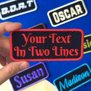May include: A black rectangular patch with red embroidered text that reads "Your Text In Two Lines". The patch has a red border. Other patches with names like "OSCAR", "Susan", and "Madison" are also visible.