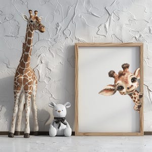 May include: A wooden giraffe figurine with brown and white markings stands beside a framed print of a giraffe peeking out. A white teddy bear with a black bow is also present. The background is a textured white wall.