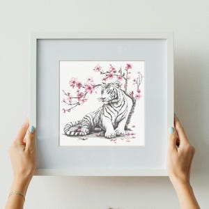May include: A white tiger sits beneath a branch of pink cherry blossoms. The tiger is looking to the left, and the blossoms are in full bloom. The image is drawn in black and white with pink accents.