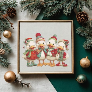Può includere: Un ricamo a punto croce incorniciato con quattro anatre dei cartoni animati vestite con abiti invernali festivi. Ogni anatra indossa un cappello, una sciarpa e un cappotto rossi, verdi e bianchi. Decorazioni natalizie.