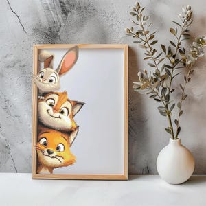 May include: A framed cross-stitch artwork featuring three cartoon animals: a rabbit, a chipmunk, and a fox. The animals are stacked, peeking out from behind the frame. The frame is made of light-colored wood. A white vase with greenery is to the right.