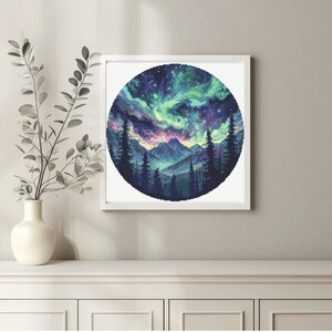 Puede incluir: Una impresi&oacute;n circular enmarcada de una cordillera con una aurora boreal vibrante en el cielo. Las monta&ntilde;as est&aacute;n silueteados contra el cielo colorido, que est&aacute; lleno de estrellas.