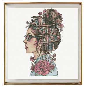 Op de afbeelding: Een kruissteekpatroon van een vrouw met een stapel boeken op haar hoofd, omringd door bloemen. De vrouw draagt een bril en heeft een roos op haar schouder.