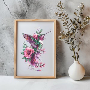 May include: A framed cross-stitch embroidery featuring a hummingbird with pink and green feathers, perched on a branch with pink flowers.