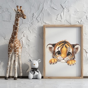 Può includere: Una stampa incorniciata di un simpatico cucciolo di tigre con strisce arancioni e nere, una statuina di giraffa e un orsacchiotto bianco con un fiocco nero. La giraffa è marrone e bianca. Gli oggetti sono su una superficie bianca.